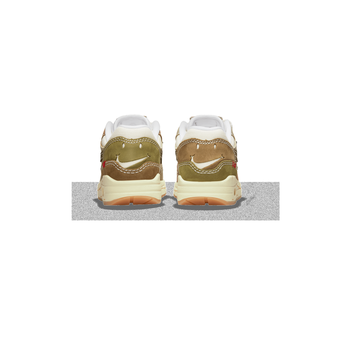 Rear view of a pair of Nike Air Max 1 Premium sneakers in beige, olive, and brown tones with a smiley-face design formed by the heel stitching and swoosh logo, set on a cream midsole with gum outsole.