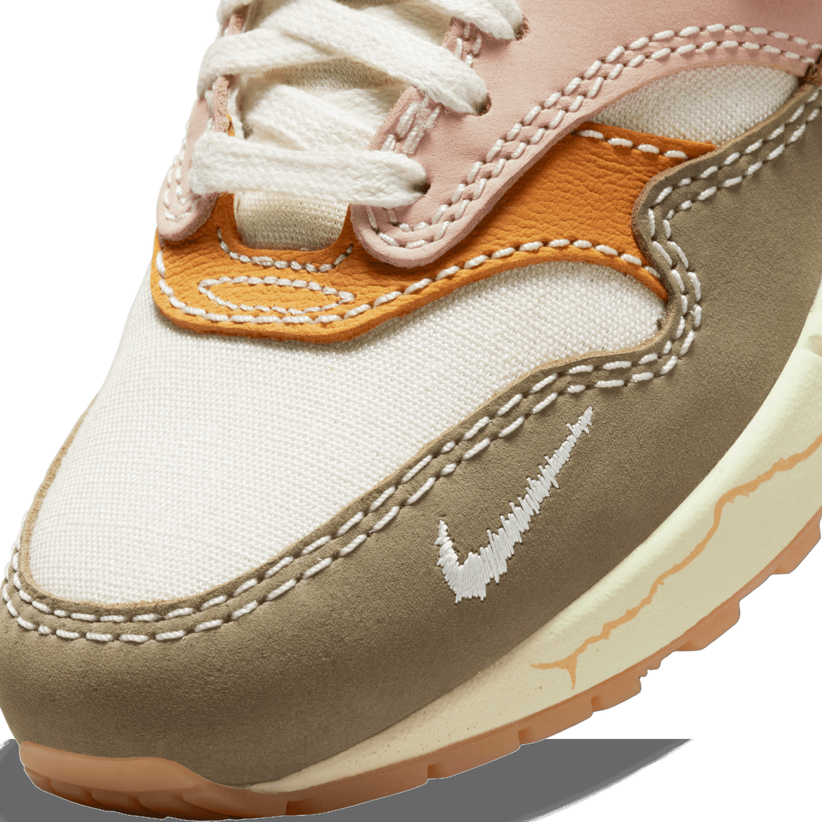 Close-up of the toe box and swoosh on a beige, brown, orange and pink Nike Air Max 1 Premium Wabi-Sabi sneaker showing visible stitching and canvas texture