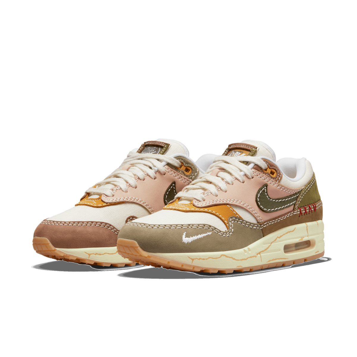 Pair of Nike Air Max 1 sneakers in a beige, brown, pink and olive color-block design with a cracked cream midsole and red XXV stitching on the heel, angled toward the left