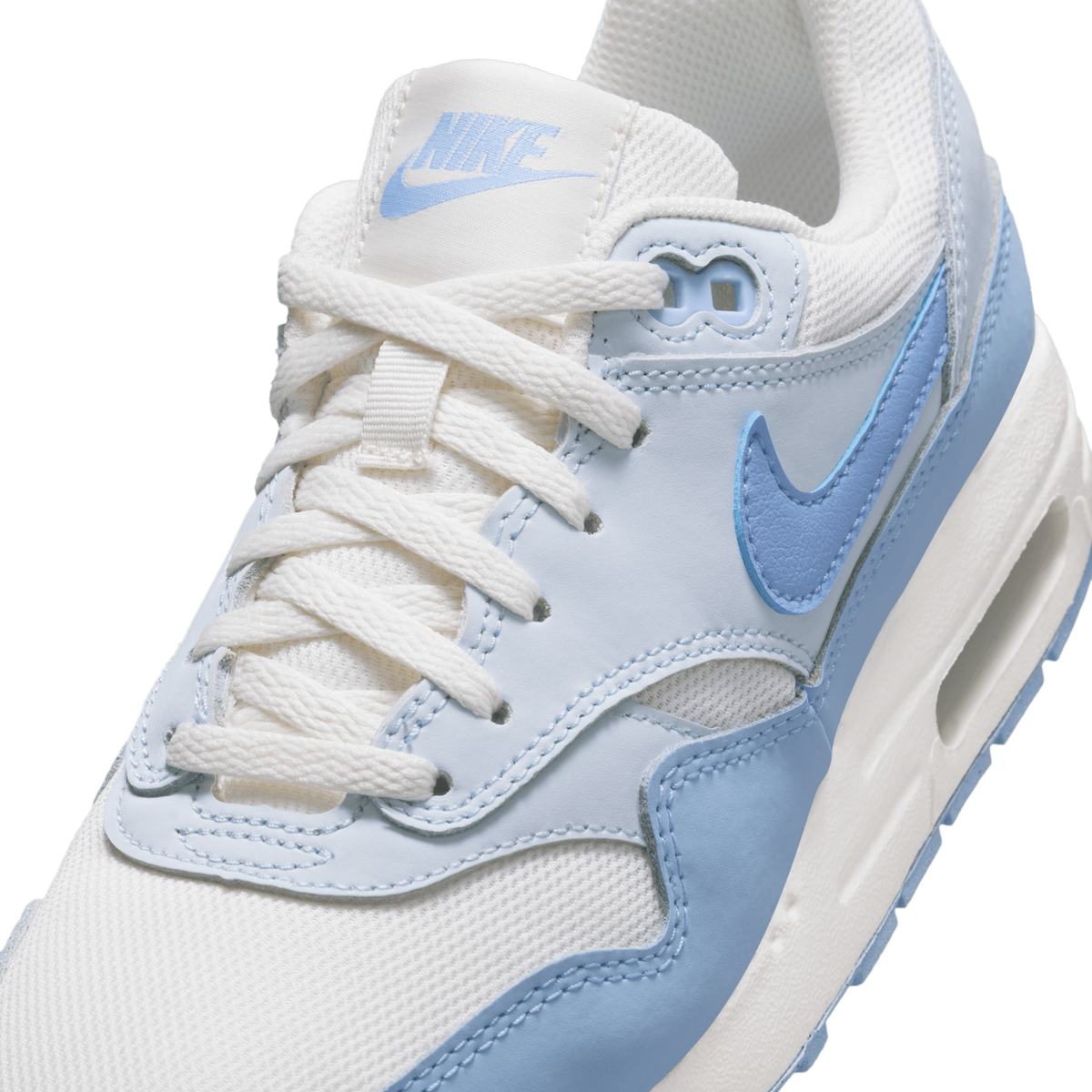 Close-up angled view of a white and blue Nike Air Max 1 showing the tongue with blue Nike logo, laces, and blue swoosh on the side panel
