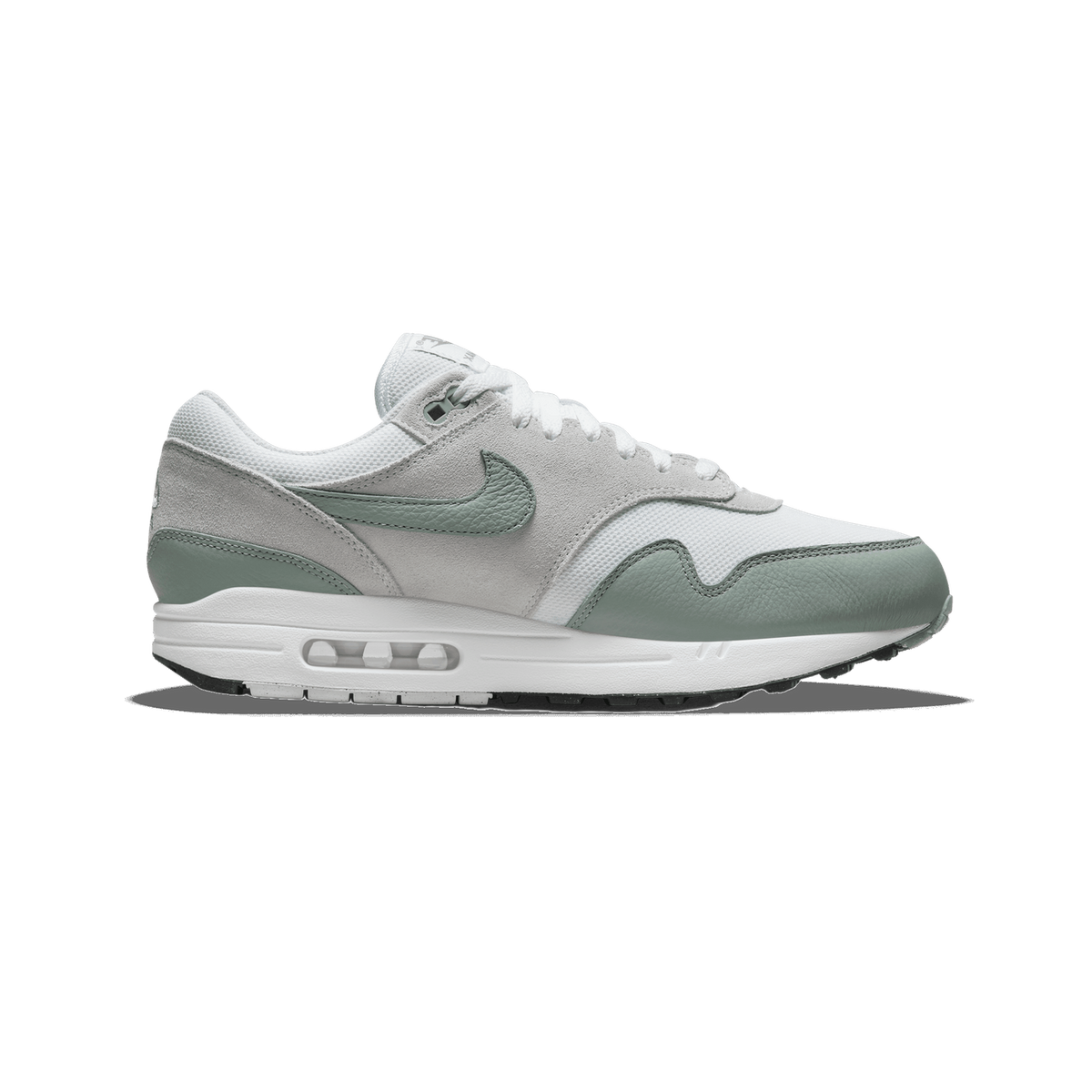 Side view of a white Nike Air Max 1 sneaker with mica green Swoosh, toe, and heel accents and a visible Air cushioning unit in the white midsole