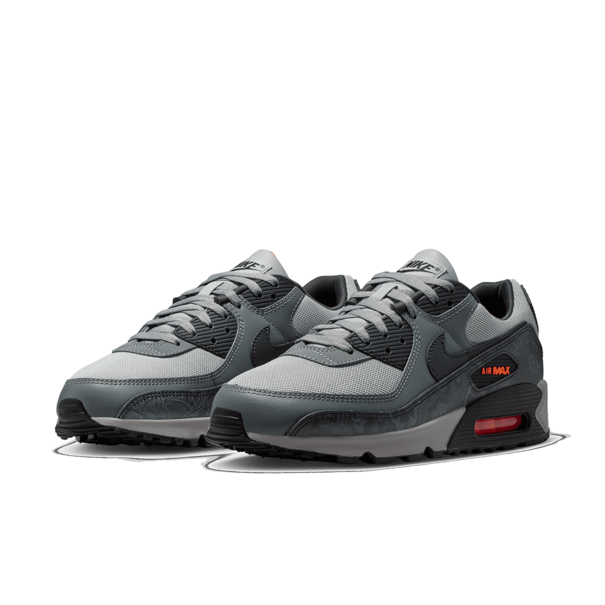 Pair of grey and black Nike Air Max 90 sneakers with orange Air Max branding and visible heel air unit, angled toward the left