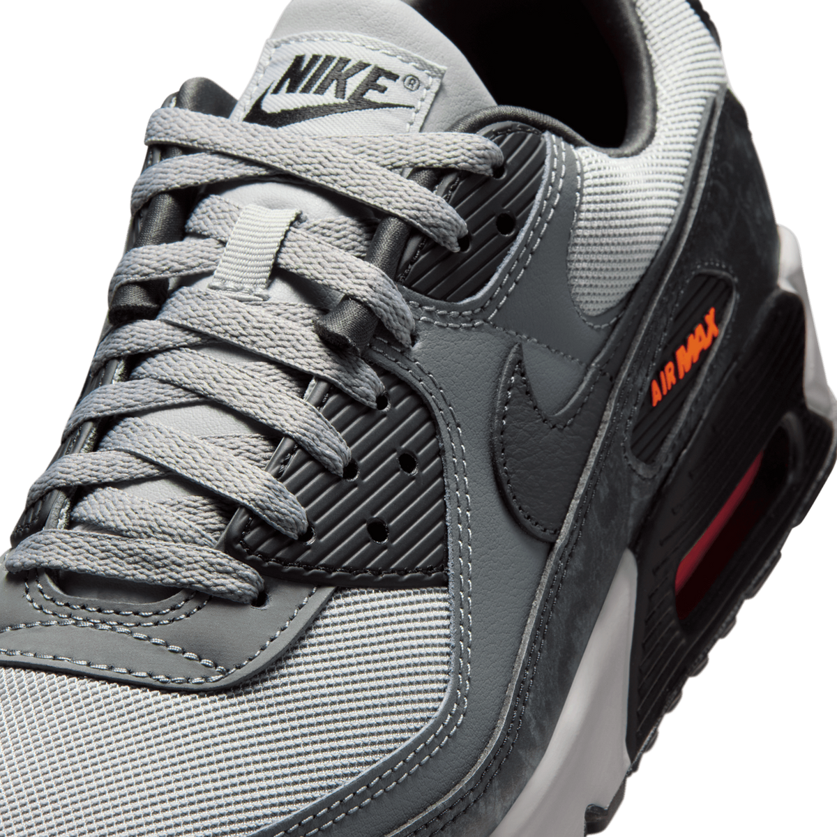 Close-up angled view of a grey and black Nike Air Max 90 showing the laces, tongue with Nike logo, swoosh, and orange Air Max text on the midsole.