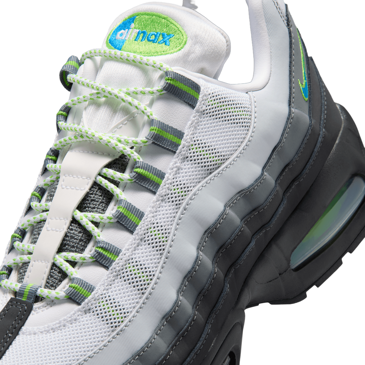 Close-up detail of a Nike Air Max 95 shoe showing the green and blue embroidered Air Max logo on the tongue, green-and-grey striped lace loops, white and green braided laces, white mesh panels, and the grey and black layered midsole with a visible gr