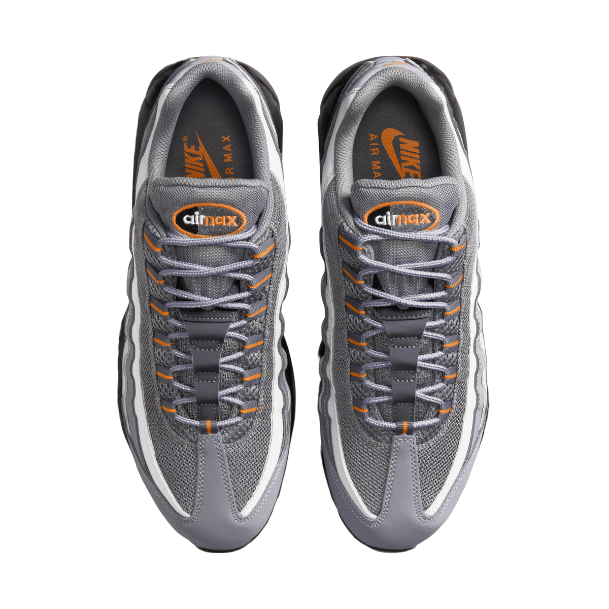 Top-down view of a pair of grey Nike Air Max 95 sneakers placed side by side with toes pointing up, showing grey mesh and suede panels, white accents, orange laces and Air Max branding on the insoles.