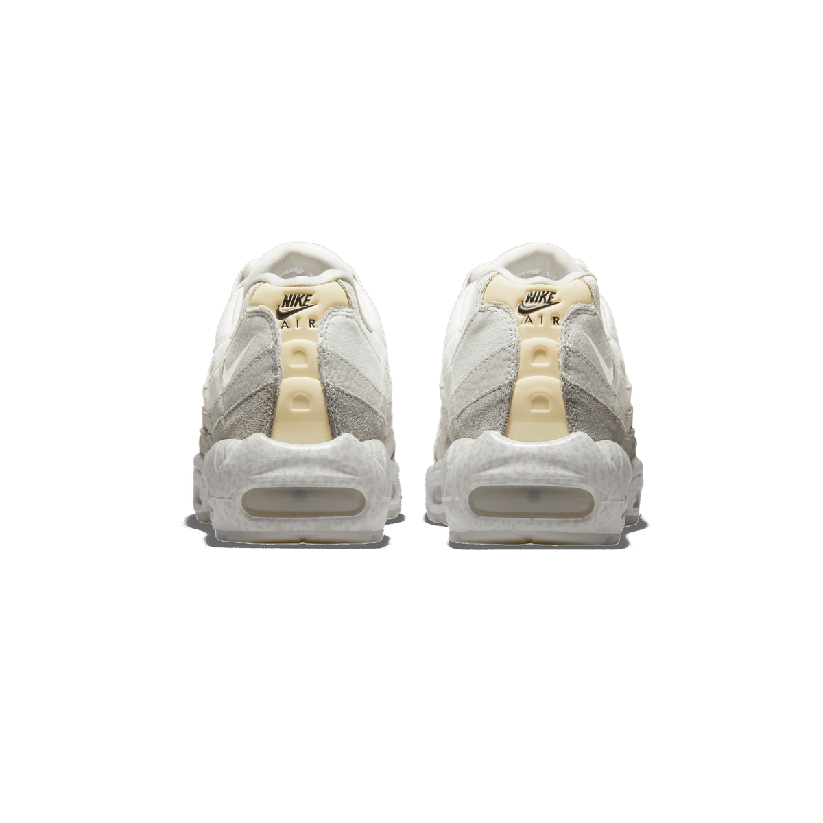 Rear view of a pair of Nike Air Max 95 sneakers in off-white and light grey tones, with cream-yellow heel tabs bearing black Nike and Air logos and a speckled light-grey midsole at the heel.