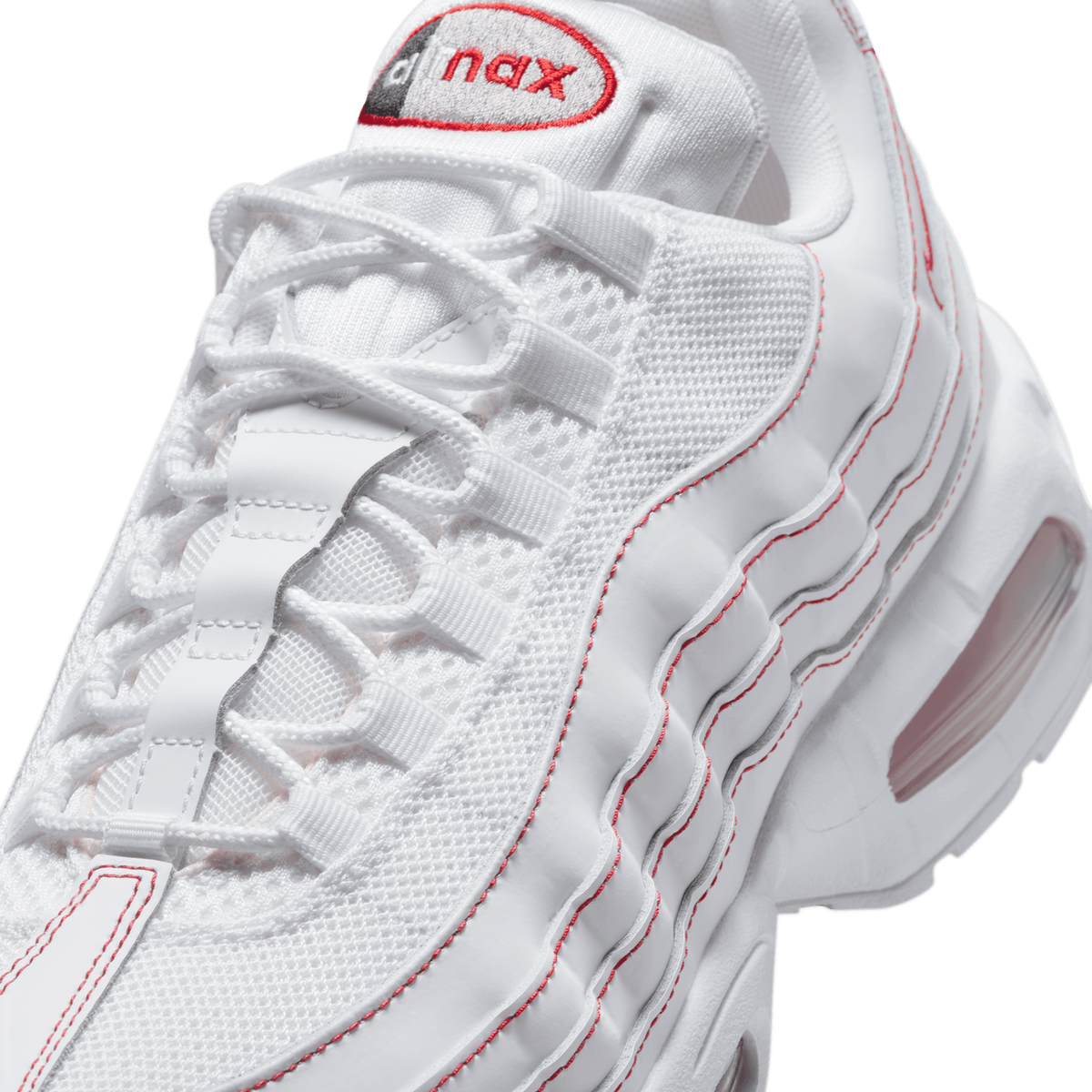 Close-up detail of a white Nike Air Max 95 showing the red-outlined embroidered 'nax' heel tab, white laces and mesh panels, and red stitching along the layered overlays, with a visible pink-tinted Air unit in the midsole.
