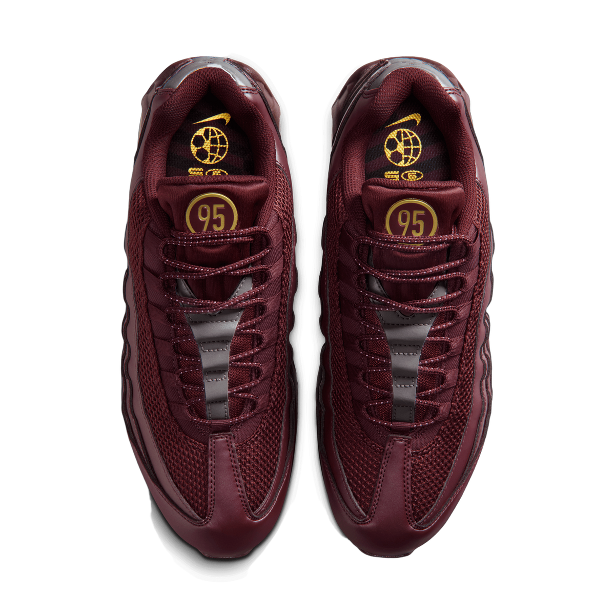 Top-down view of a pair of burgundy Nike Air Max 95 sneakers placed side by side, showing the mesh and leather uppers, the lacing, the gold '95' heel tab, and the gold Nike logo and globe graphic on the insoles.