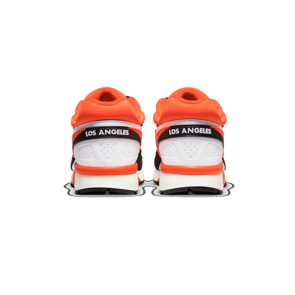 Rear view of a pair of Nike sneakers with orange heel tabs, white heel panels, black trim, and 'Los Angeles' text on the heel straps above white midsoles