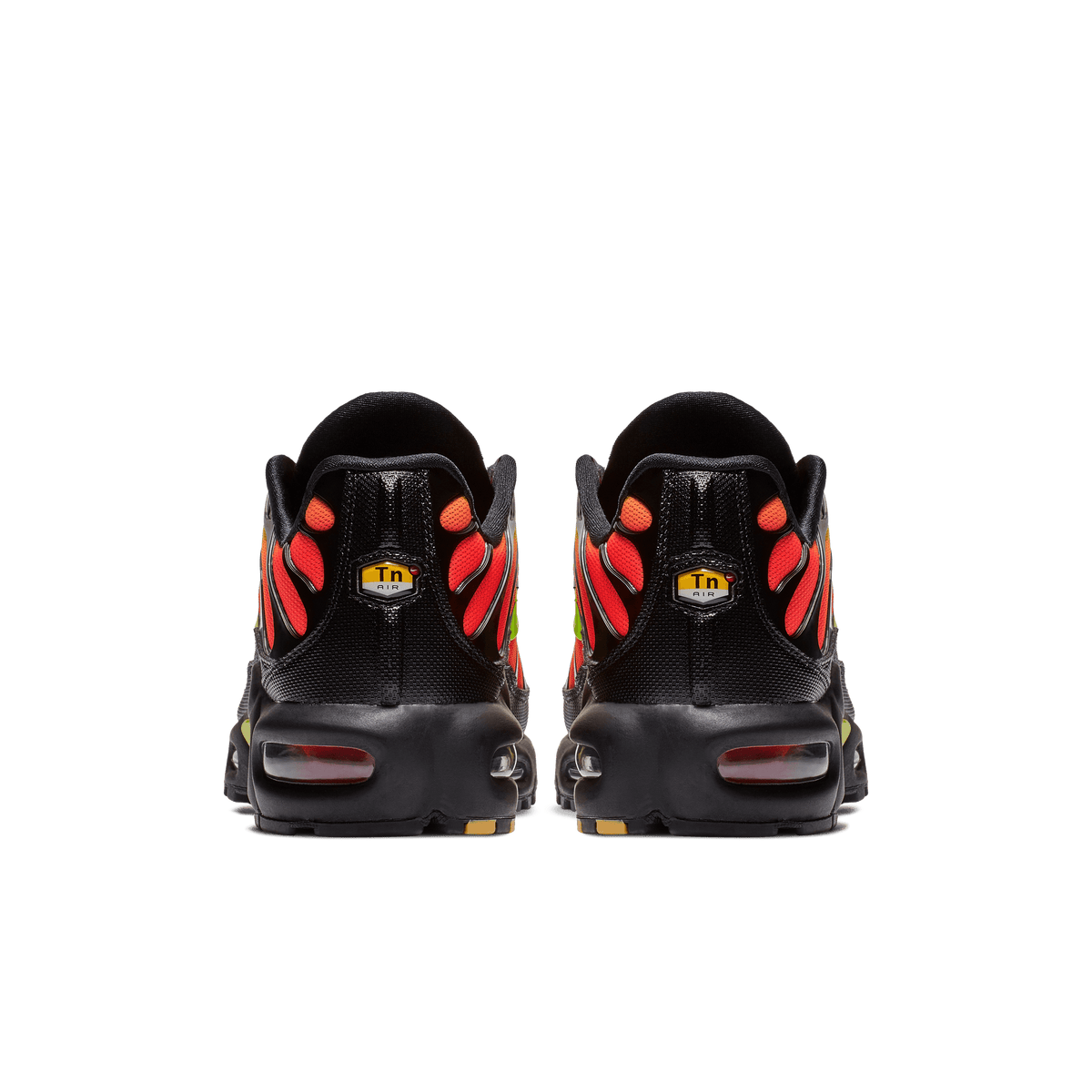 Rear view of a pair of black Nike Air Max Plus sneakers with red-orange flame-like overlays, yellow TN Air heel tags, and visible red-tinted heel air units.