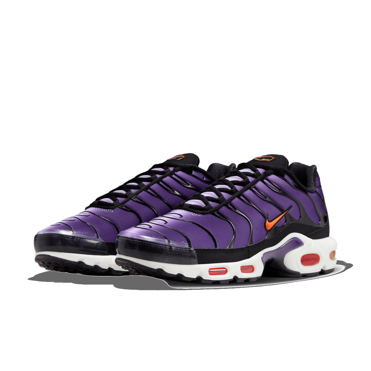 Front three-quarter view of a pair of purple and black Nike Air Max Plus sneakers with orange swoosh logos and a white midsole featuring red and black air bubble units.
