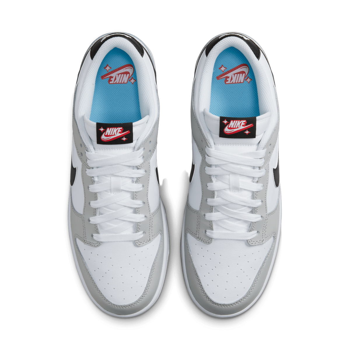 Top-down view of a pair of white and grey Nike Dunk Low sneakers with black swooshes, blue interior lining, and red Nike graphics on the tongues