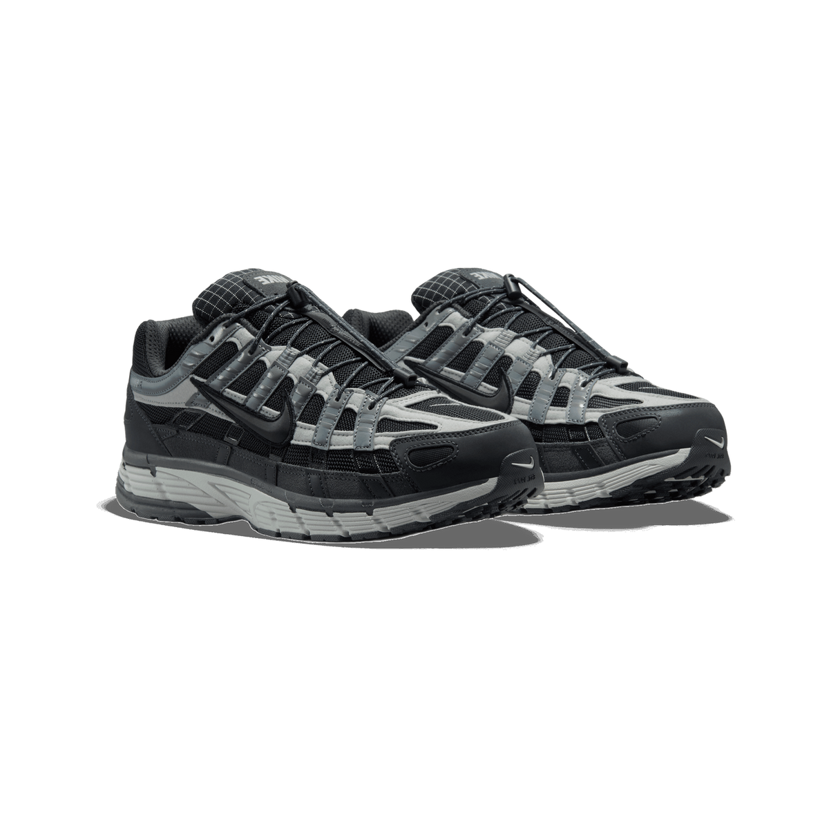A pair of Nike P-6000 sneakers in black, grey and dark grey, angled toward the left with their toes pointing forward, showing the mesh and suede panels, elastic lace toggles, and the Swoosh on the sides.