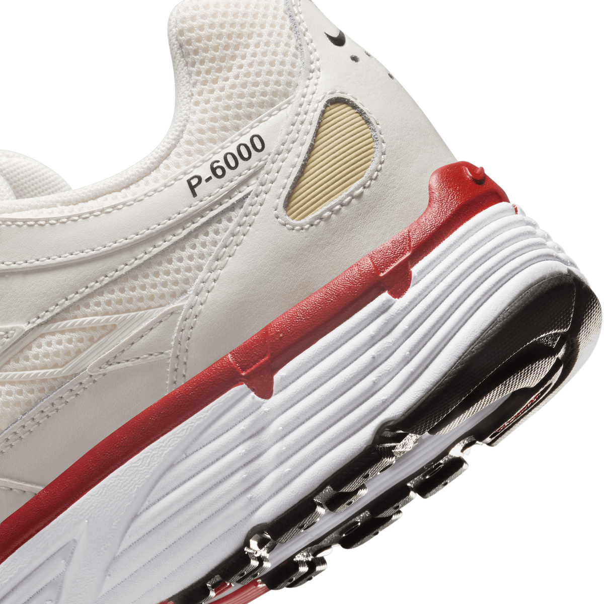 Close-up of the heel and lower side of a white Nike P-6000 sneaker showing the 'P-6000' text on the upper, a red accent along the midsole, a white ribbed sole, and a black heel counter with a silver mesh detail.