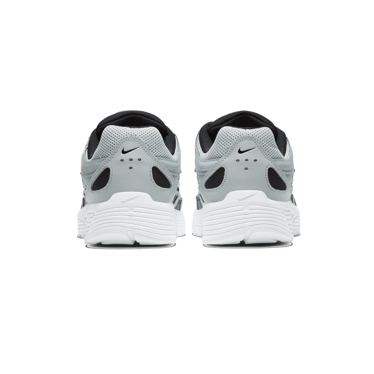 Rear view of a pair of silver and grey Nike P-6000 sneakers with white soles and black pull tabs, showing the heel counters with small Nike Swoosh logos.