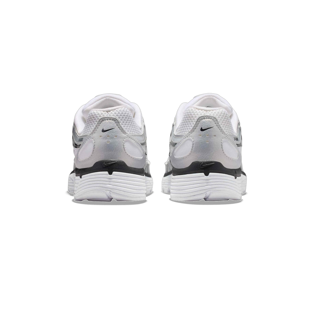 Rear view of a pair of white and silver Nike P-6000 sneakers showing the heel counters with black Nike logos and ridged white outsoles.