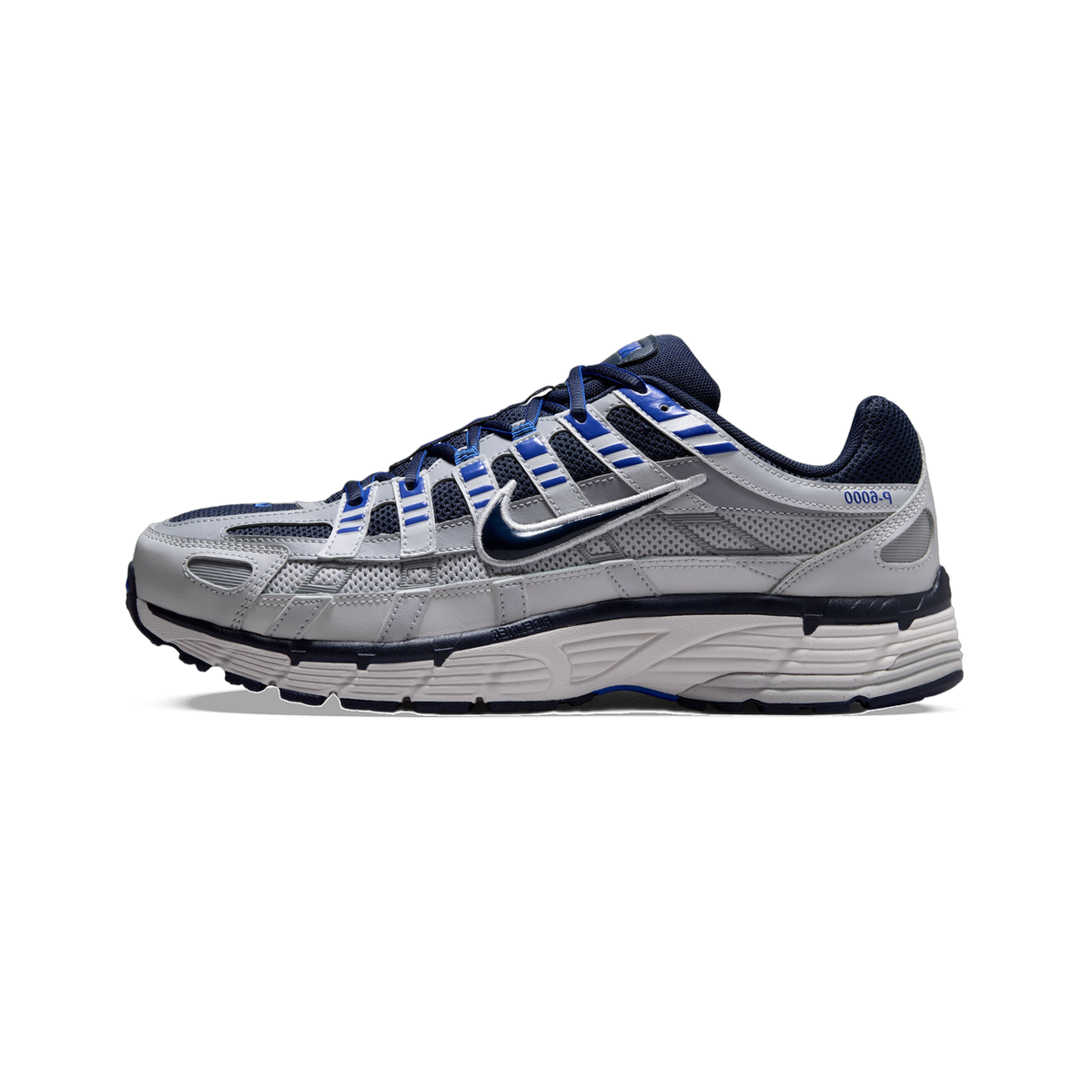 Lateral view of a grey Nike P-6000 sneaker with navy and blue accents, layered mesh panels, and a chunky ridged white midsole.