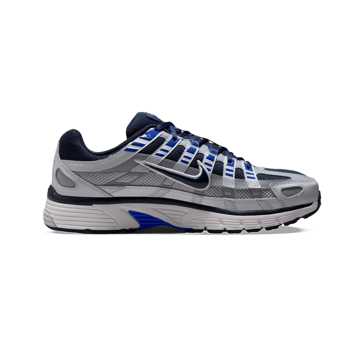 Lateral view of a grey Nike P-6000 sneaker with navy blue mesh panels, blue lace loop accents, and a white ridged midsole.