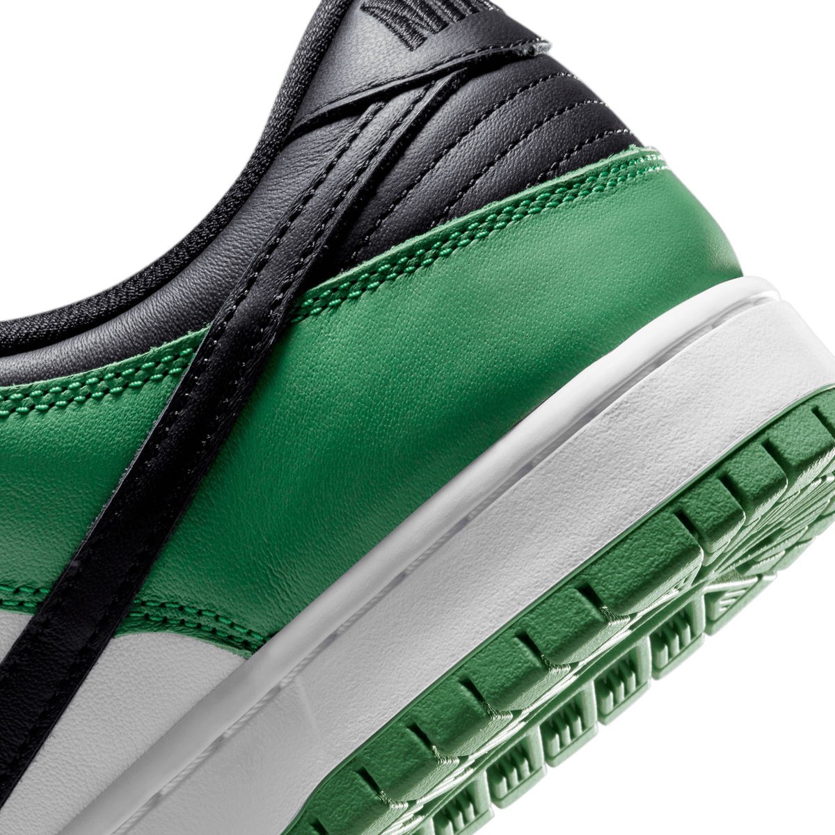 Extreme close-up of a Nike SB Dunk Low toe box and sole showing green and white leather panels, black swoosh, and green lugged outsole