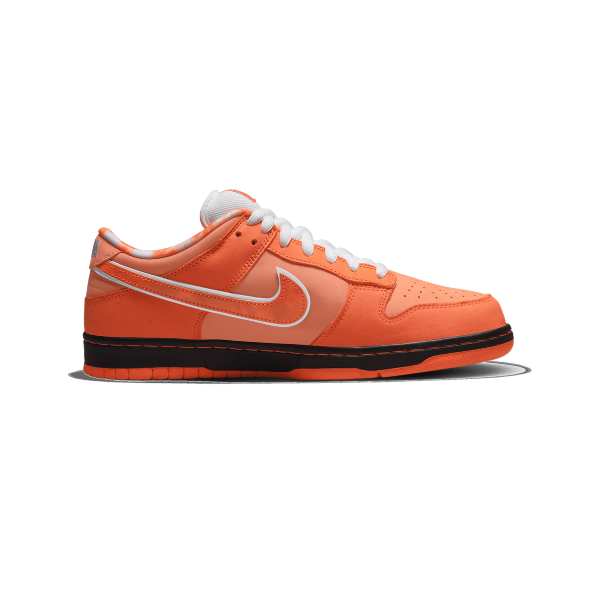 Left orange Nike SB Dunk Low sneaker shown from the side with toe pointing left, featuring a white swoosh, white laces, and a black midsole with orange outsole