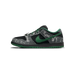 Side view of a black and grey Nike SB Dunk Low with green swoosh, lace charm, green laces, and white line-art graphics on the heel and toe panels