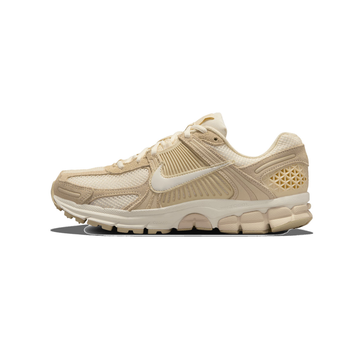 Side profile of a single cream and tan Nike Zoom Vomero 5 sneaker with the toe pointing left, showing a white Swoosh logo on beige suede and mesh overlays, cream laces, and a pale sole with visible Nike Zoom and Cushlon branding.