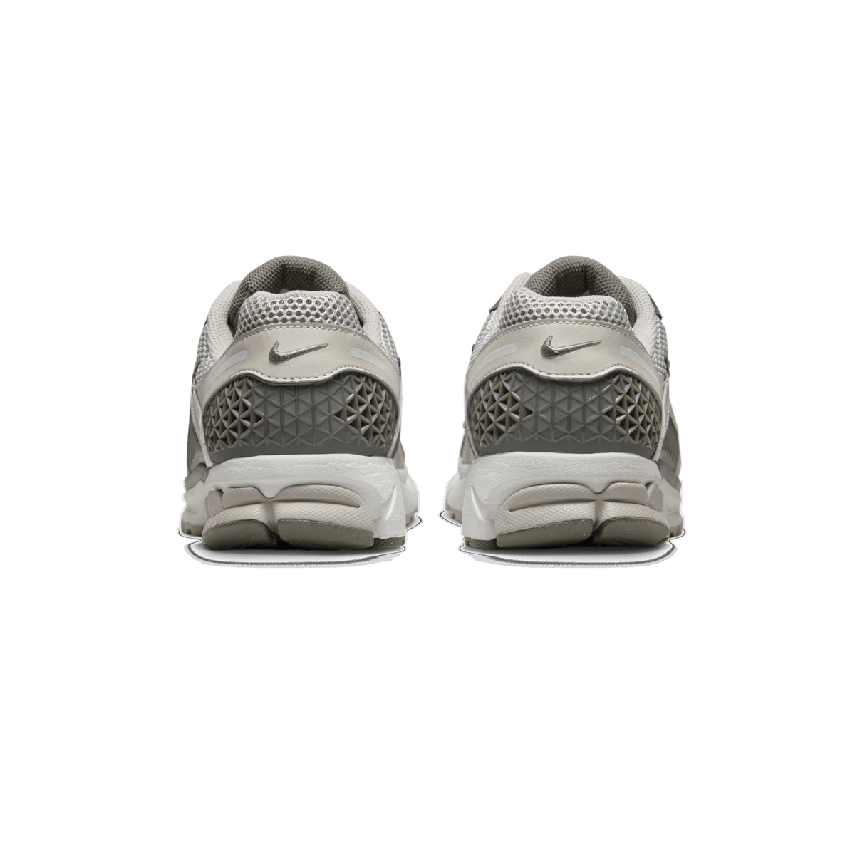 Rear view of a pair of grey, beige and white Nike Zoom Vomero 5 sneakers standing side by side, showing the heel tabs with embossed Swoosh logos, mesh collars, and textured grey heel counters.