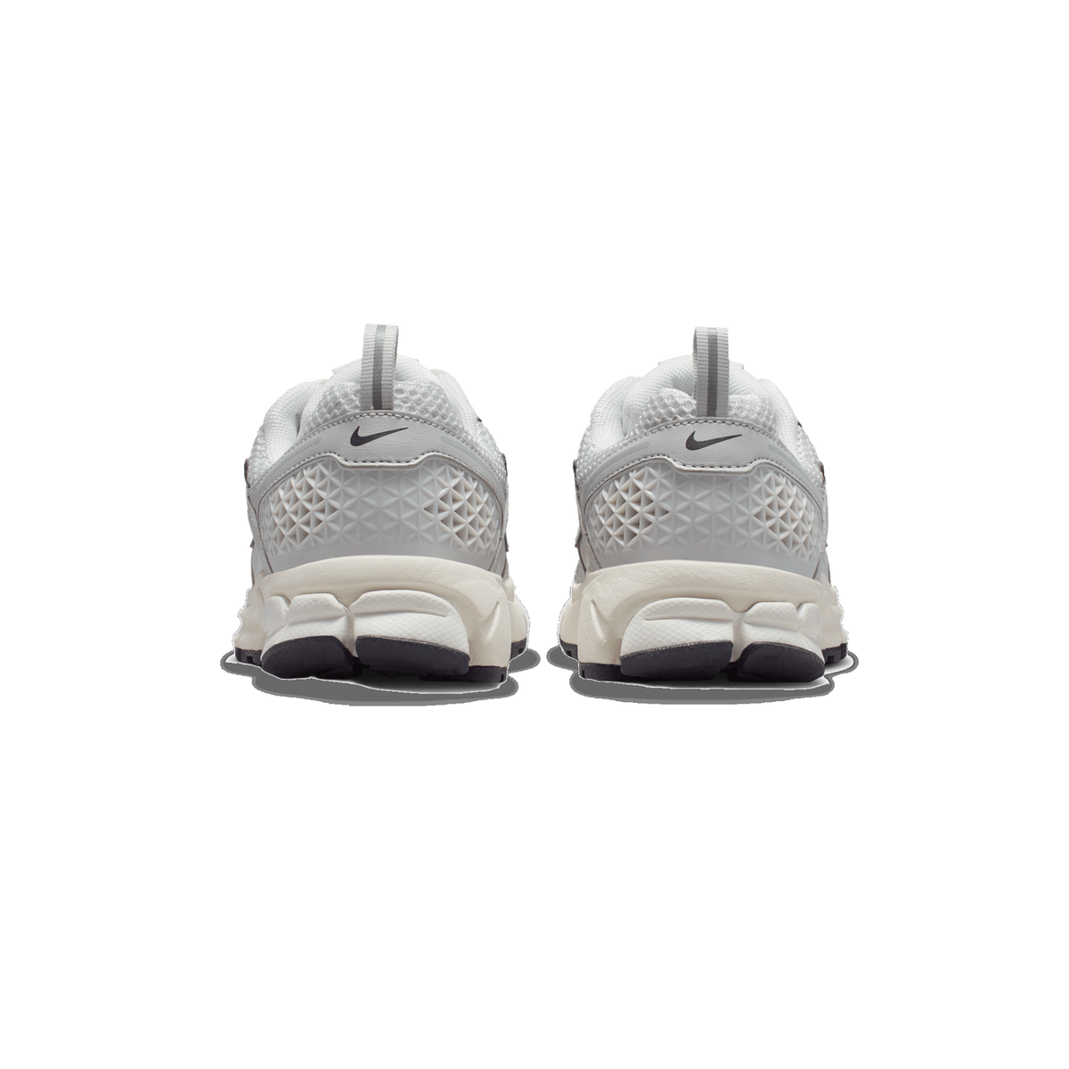Rear view of a pair of grey and white Nike Zoom Vomero 5 sneakers on a white background, showing the heel tabs, the Nike swoosh on each heel, and the textured grey heel panels and cream midsole.