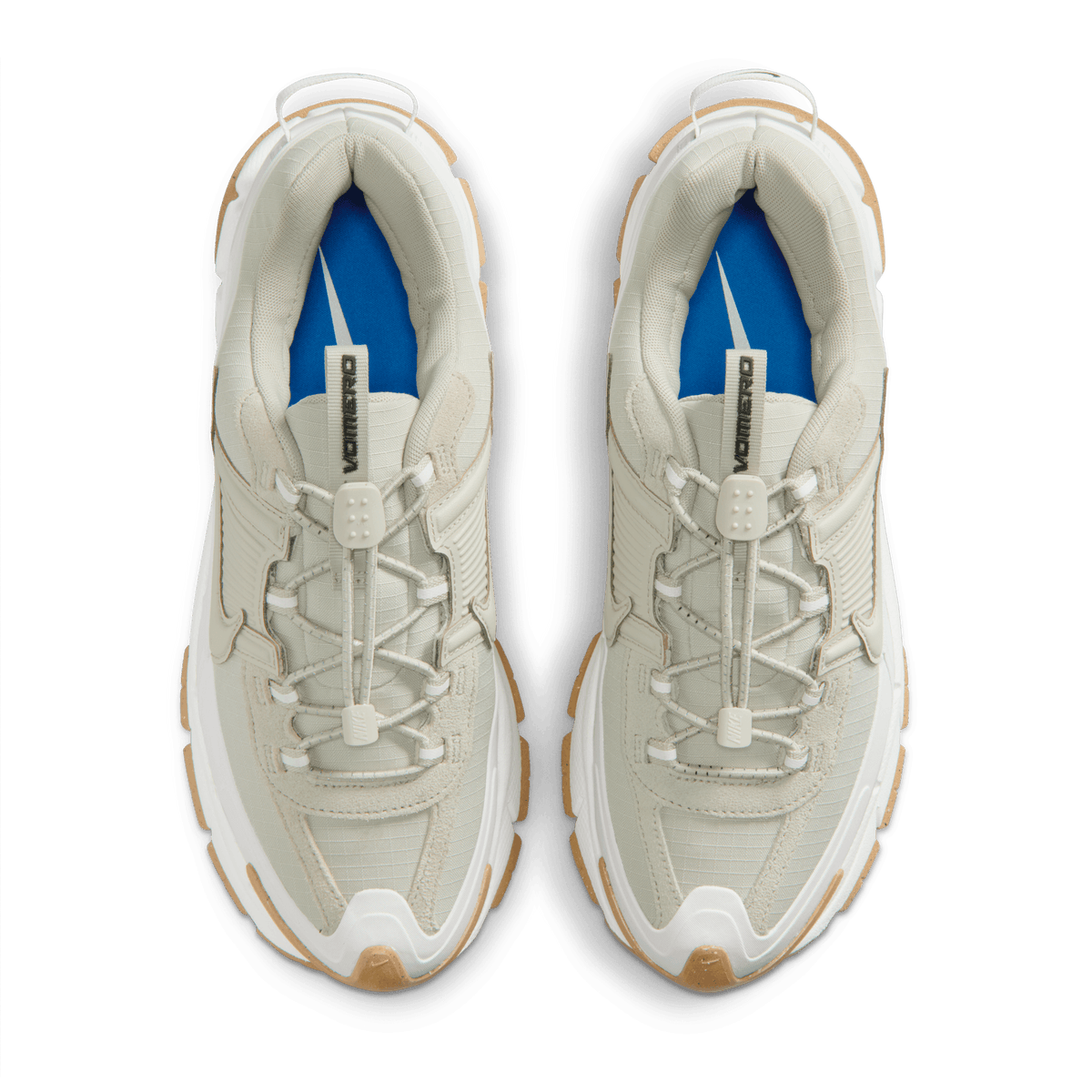 Top-down view of a pair of Nike Zoom Vomero 5 sneakers in sail and light stone with gum outsoles, blue interior lining, and toggle lace closures labeled Vomero.