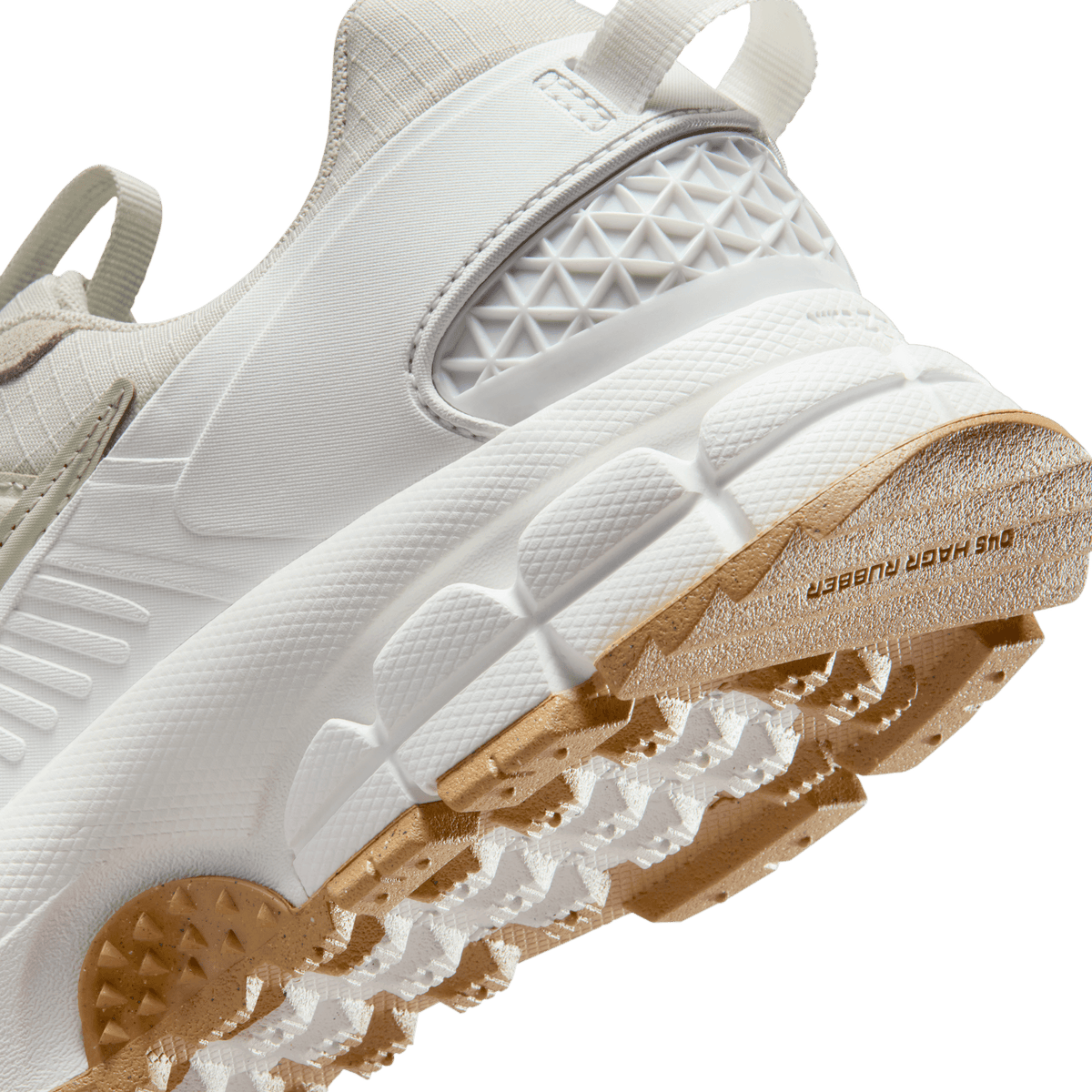 Close-up of the Nike Zoom Vomero 5 outsole in sail and light stone with a gum rubber heel showing durable rubber tread lugs and textured midsole pattern