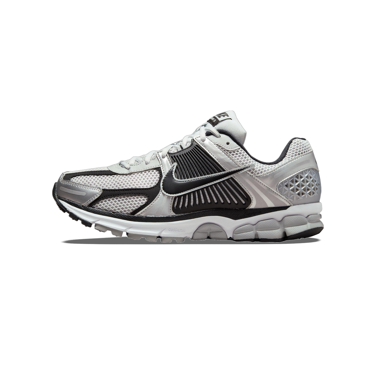 Side view of a Nike Zoom Vomero 5 running shoe in silver, black and white with mesh upper and chunky white midsole, toe pointing left.