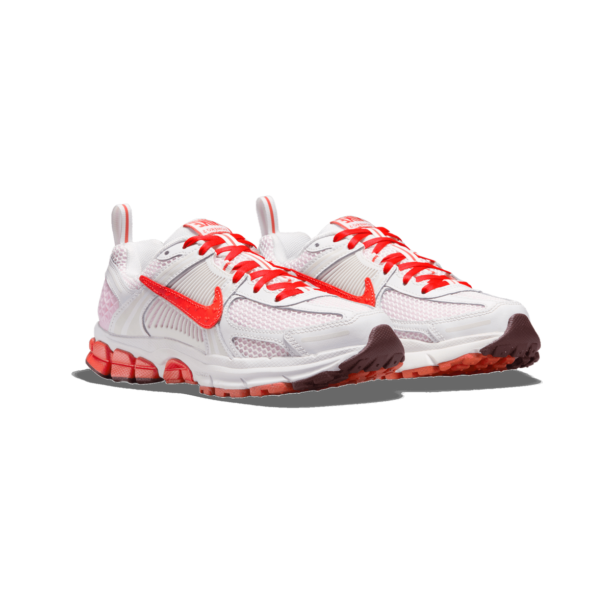 A pair of white and red Nike Zoom Vomero 5 sneakers angled side by side, showing red laces, red Swoosh logos, white mesh uppers, and red-and-white lugged soles.