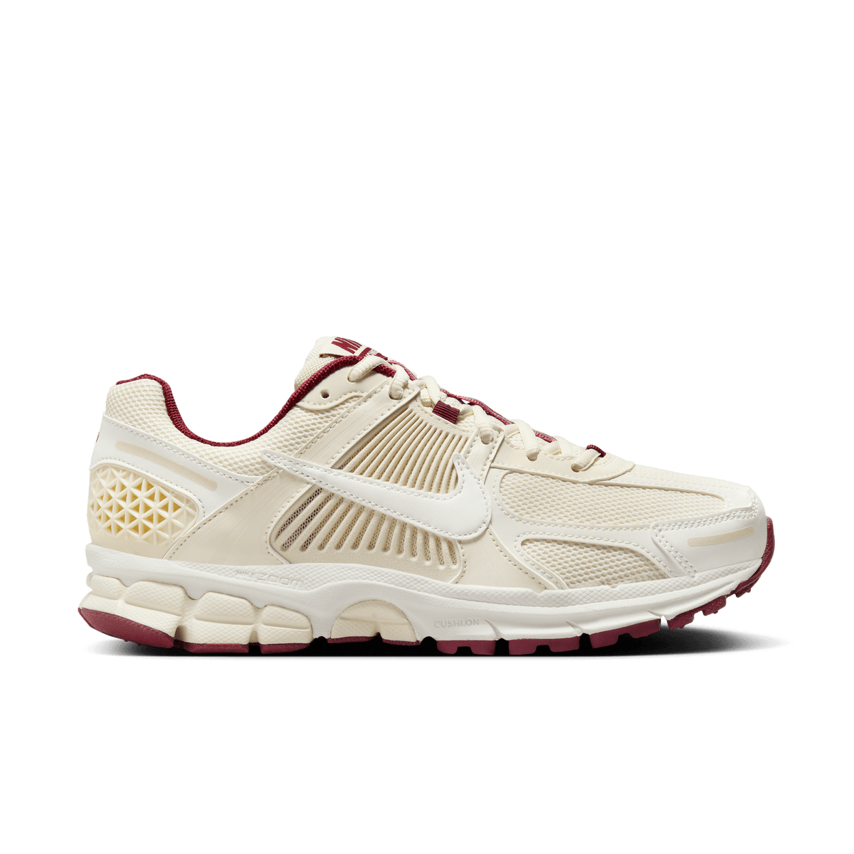 Side view of a cream Nike Zoom Vomero 5 sneaker with dark red lace accents, heel tab, and outsole, featuring a white Swoosh and textured panel detailing