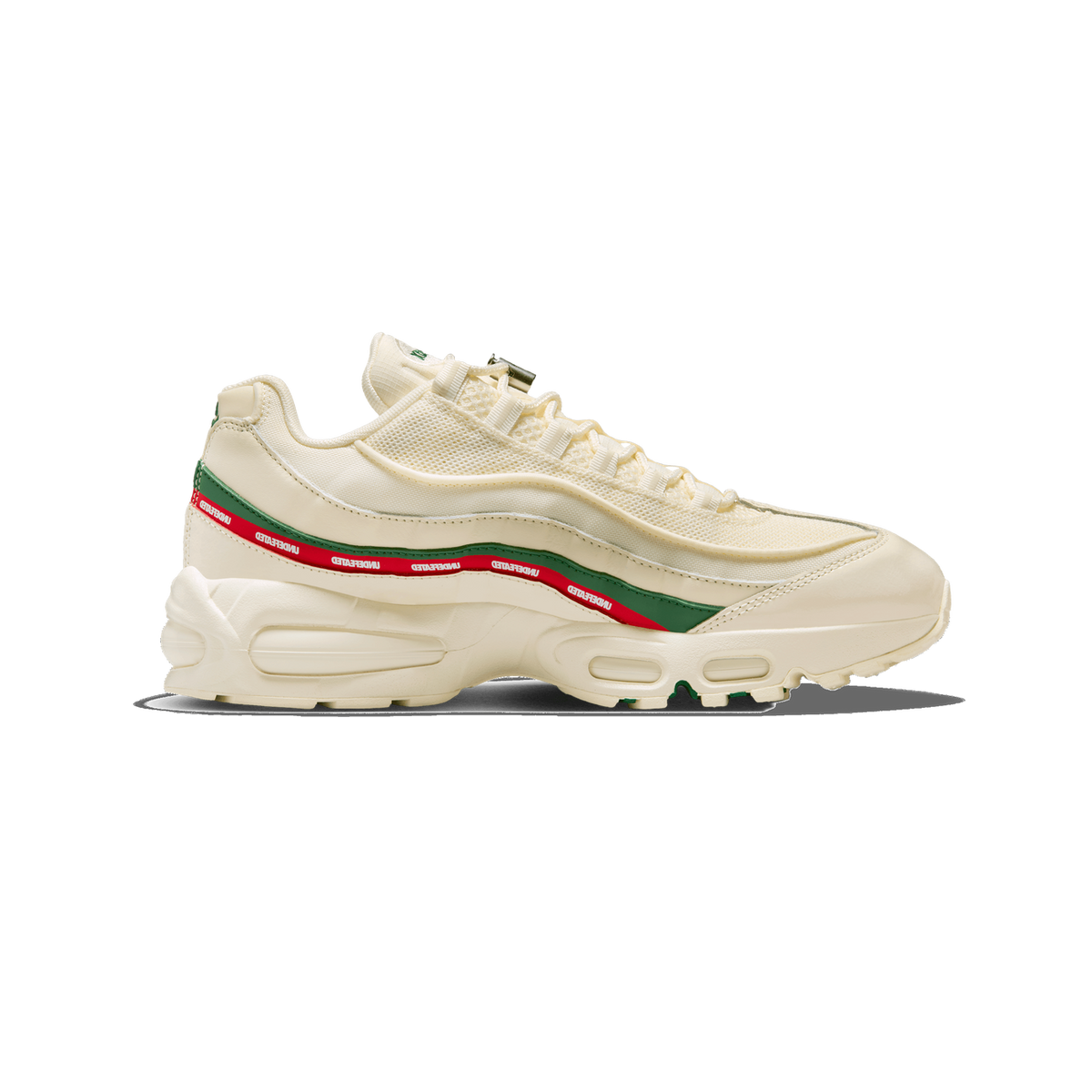 Side profile of a cream-colored Nike Air Max 95 sneaker with the toe pointing left, showing a green and red stripe with repeated white UNDEFEATED text along the midsole, a mesh and leather upper, and visible Air Max units in the sole.