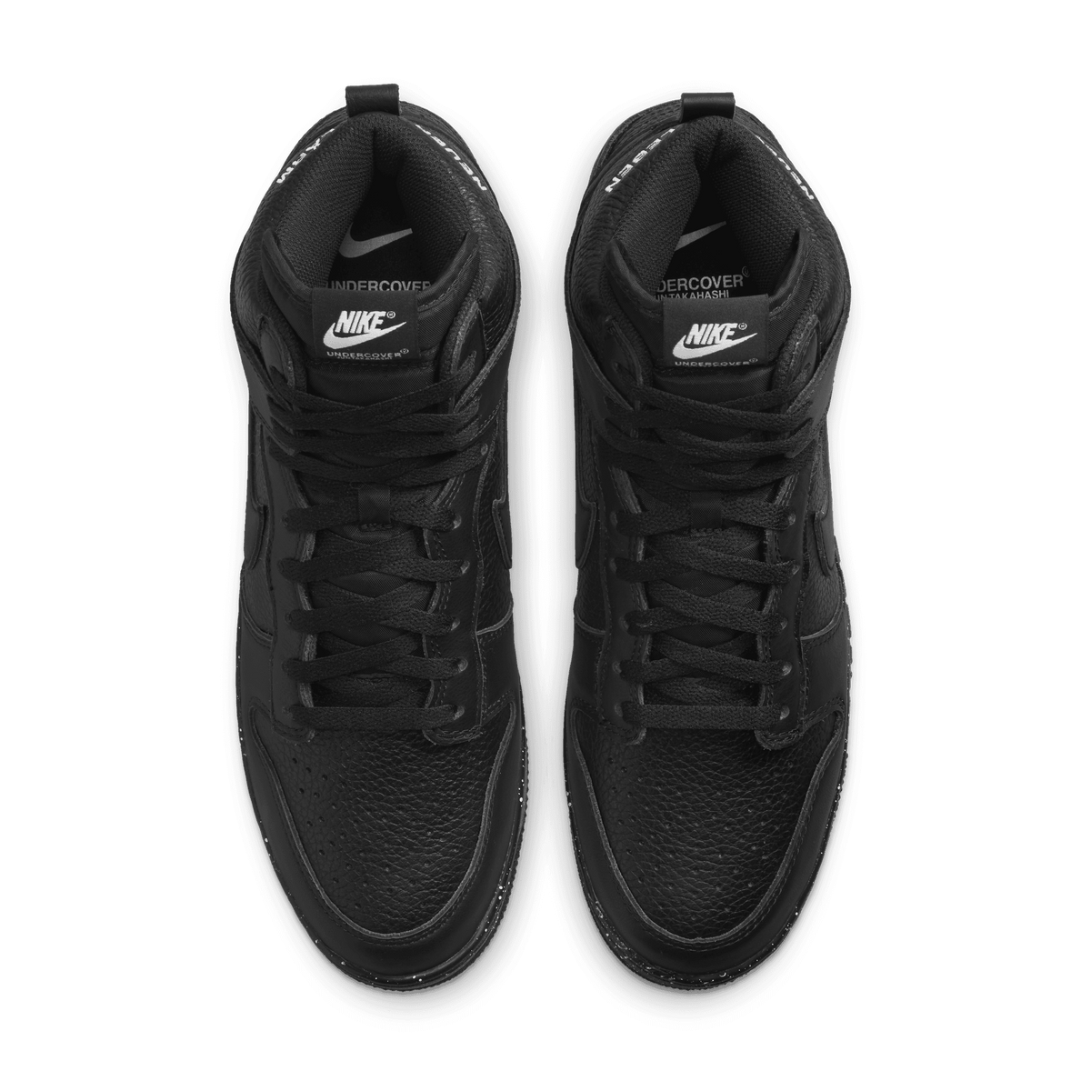Top-down view of a pair of black Nike Dunk High Undercover Chaos sneakers showing the laces, Nike and Undercover branded tongue tags, and speckled midsole detail.