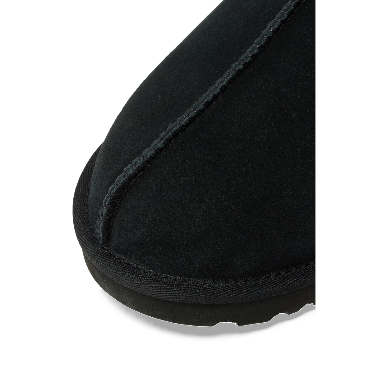 Close-up of the toe area of a black UGG Tasman II suede slipper showing the stitched seam and textured sole edge.