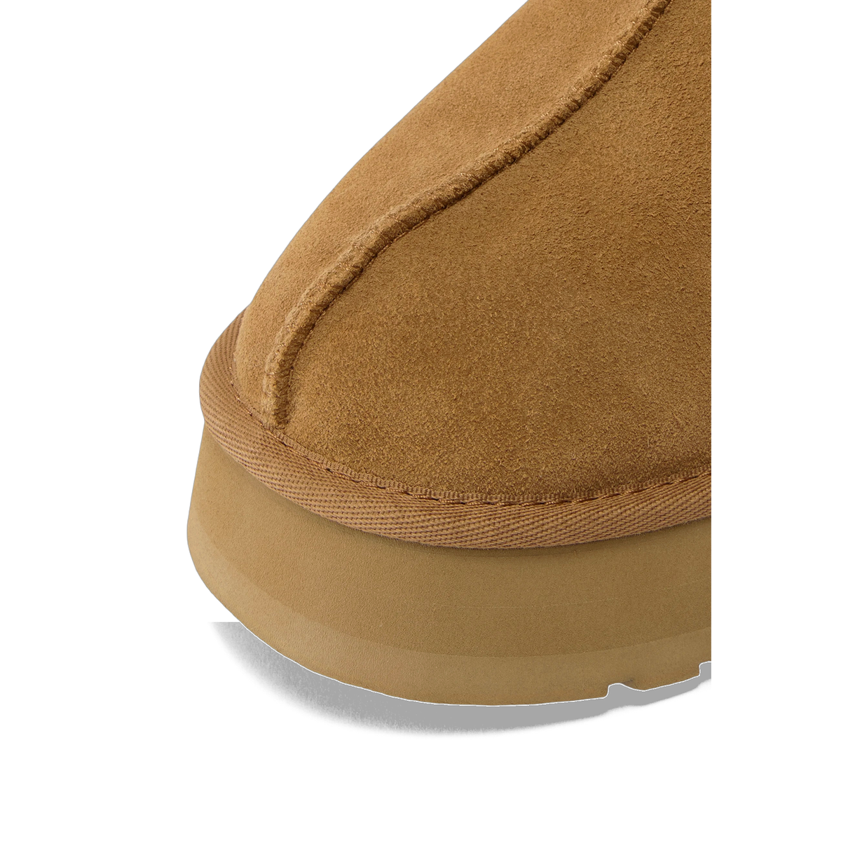 Close-up view of the toe and sole area of a chestnut brown suede slipper showing the seam stitching and textured sole edge.