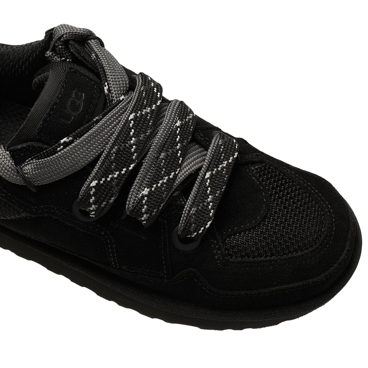 Close-up top-down view of a black UGG Lowmel Lo sneaker showing thick grey and white patterned laces, suede and mesh panels, and the UGG logo tab.