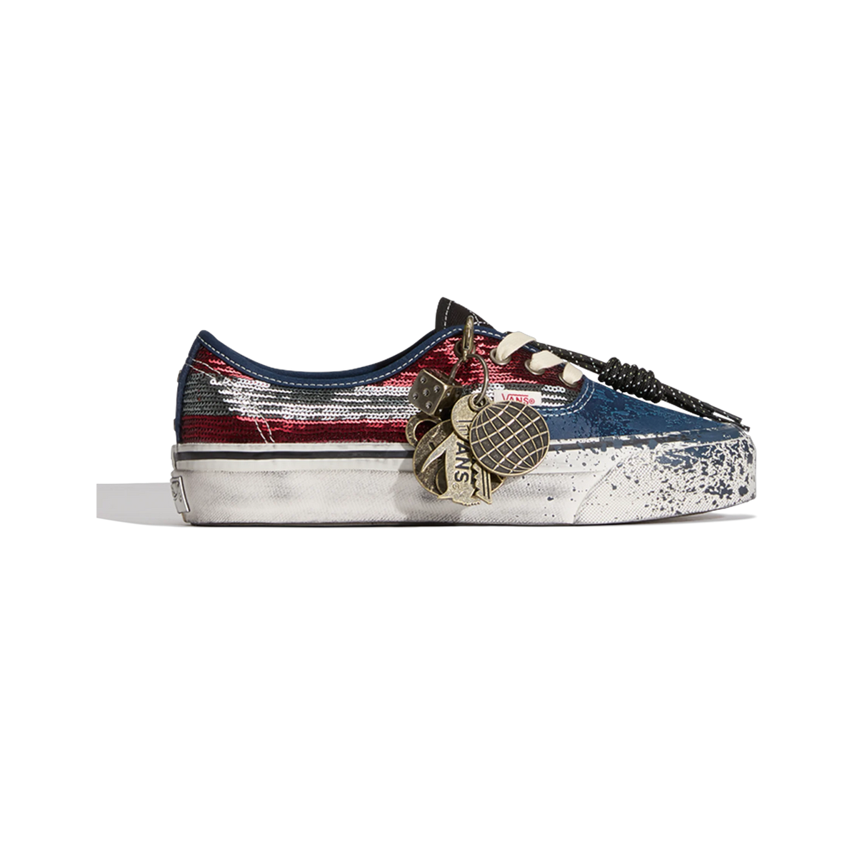 Side view of a Vans Premium Authentic La Habana sneaker with red and silver sequin toe, navy heel, distressed splattered sole, and hanging metal charm decorations including a dice and Vans tags