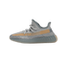 Side view of a grey knit Yeezy Boost 350 V2 sneaker with a tan side stripe panel and translucent grey outsole, toe pointing left.