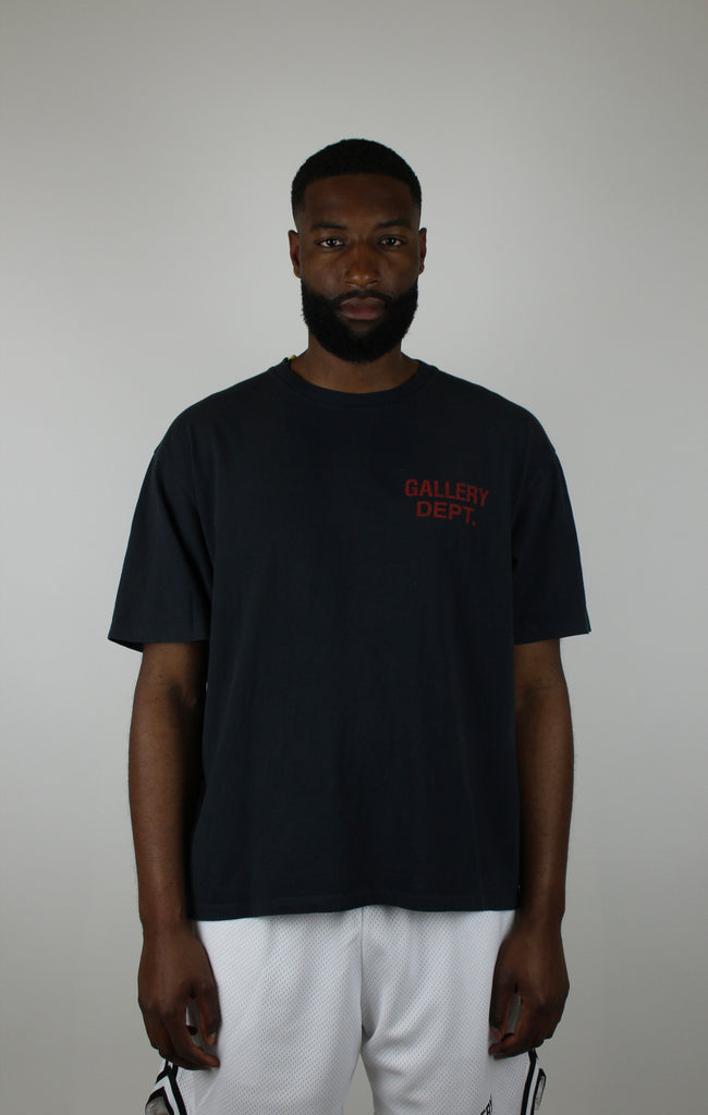 Discover the Gallery Dept. Souvenir Tee 'Washed Black' – a premium washed black short-sleeve tee with bold red lettering, blending vintage flair and modern streetwear style.