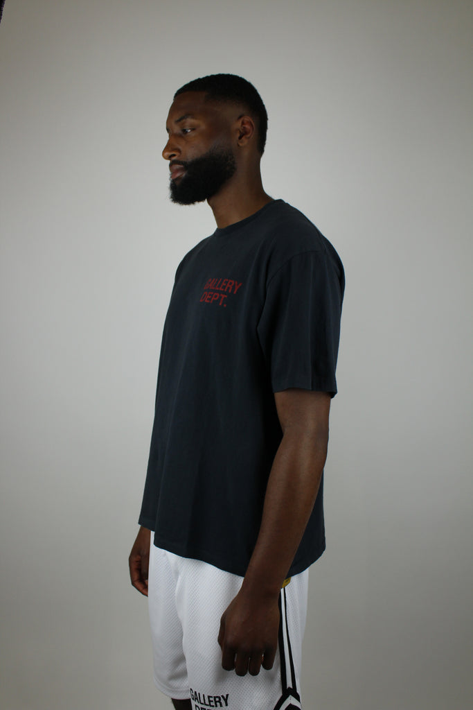 Discover the Gallery Dept. Souvenir Tee 'Washed Black' – a premium washed black short-sleeve tee with bold red lettering, blending vintage flair and modern streetwear style.