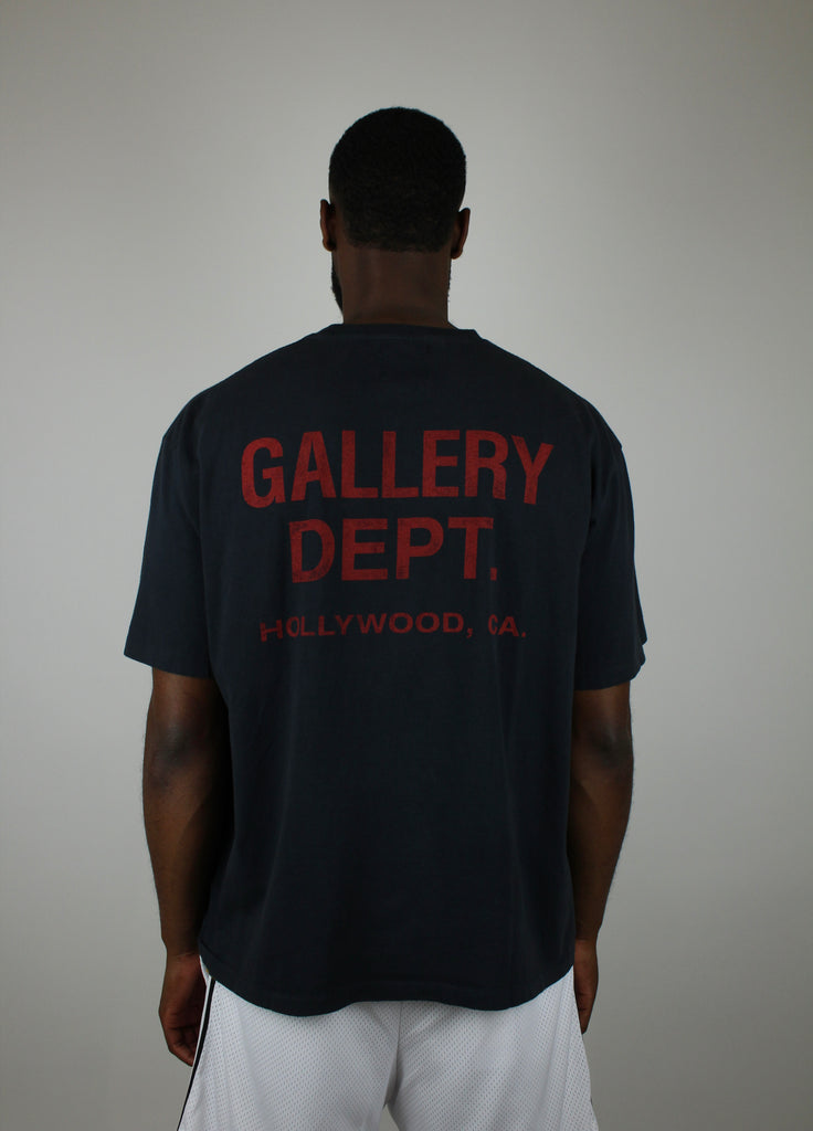 Discover the Gallery Dept. Souvenir Tee 'Washed Black' – a premium washed black short-sleeve tee with bold red lettering, blending vintage flair and modern streetwear style.