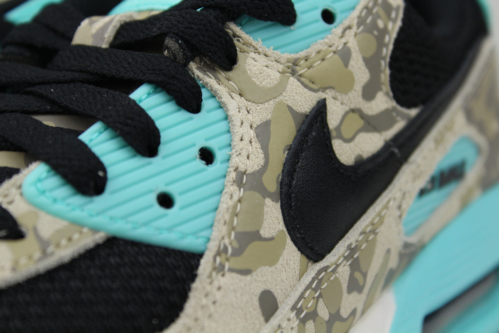 Nike Air Max 90 ‘Aurora Green’ from the 2025 Camo Pack with layered materials and bright green accents. Style with cargos and clean layers for rugged yet polished streetwear.