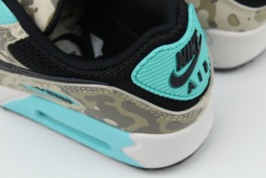 Nike Air Max 90 ‘Aurora Green’ from the 2025 Camo Pack with layered materials and bright green accents. Style with cargos and clean layers for rugged yet polished streetwear.