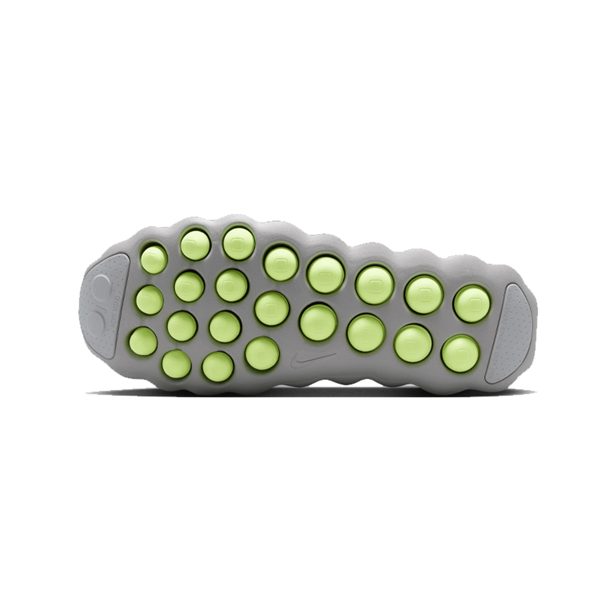 Bottom view of a grey Nike Mind 002 sole studded with rows of circular volt green traction pods and a visible Nike swoosh.