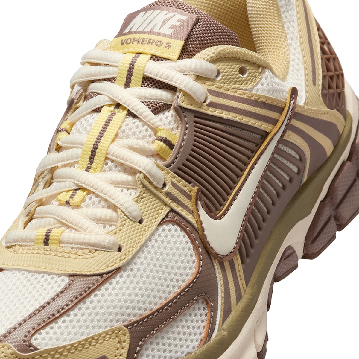 Nærbillede af en Nike Vomero 5 sneaker i mink brune og cognacfarvede nuancer, der viser overdelen i mesh, det teksturerede sidepanel, Swoosh logoet og den brandede tunge med snørebånd.